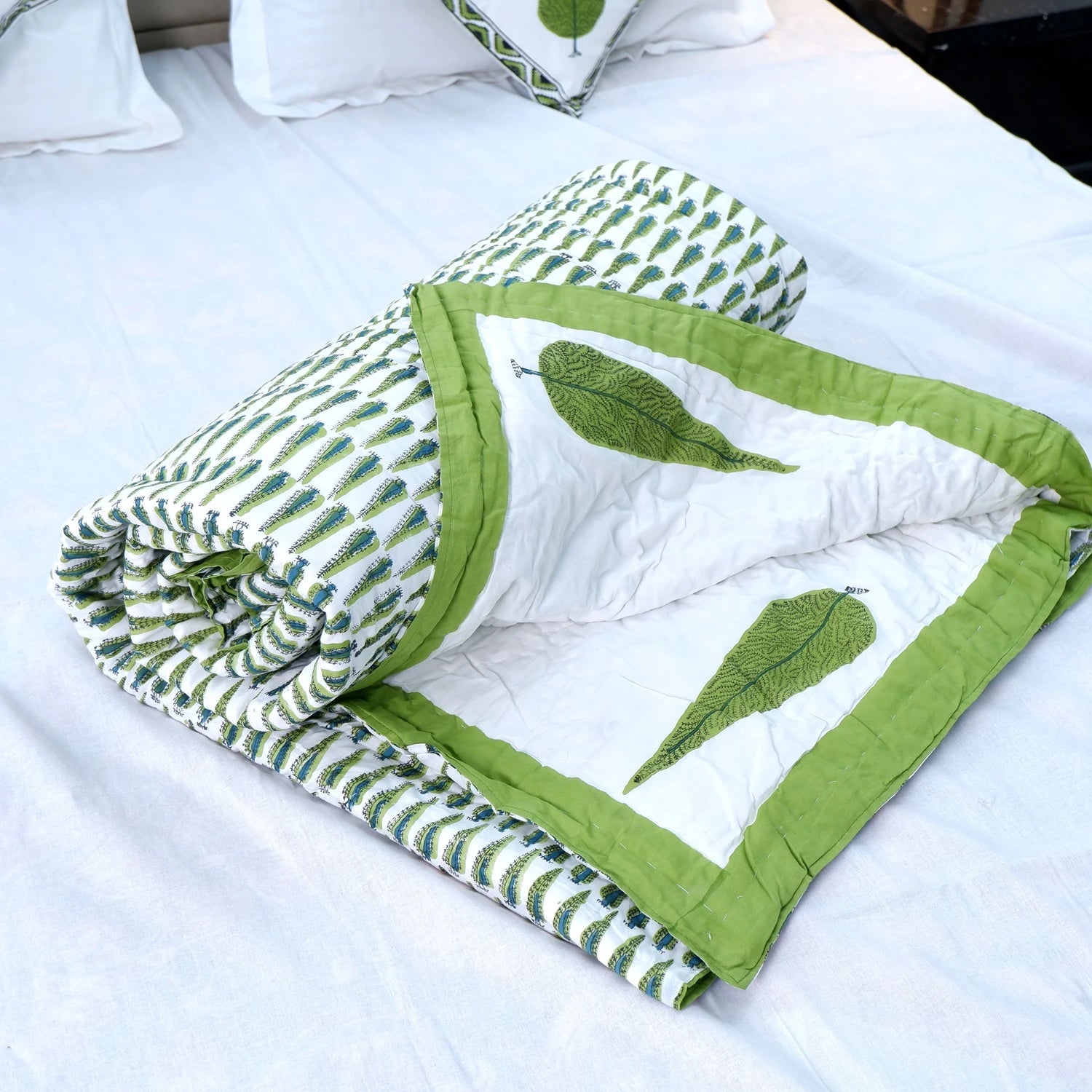 Jaipuri block print quilt set featuring green leaf designs on a white background, elegantly folded